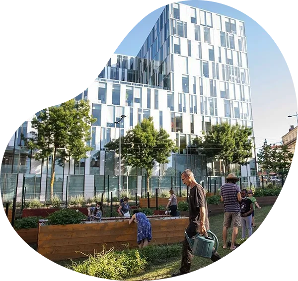 Habitants jardinant dans des bacs potagers en bois, devant un immeuble moderne en centre-ville